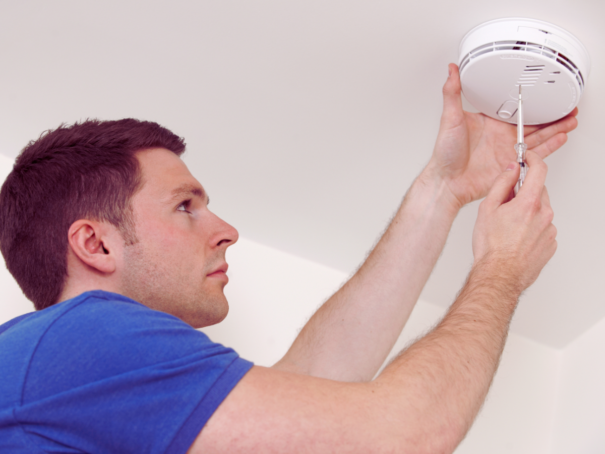 Electrician installing hardwired smoke detector